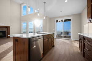 Kitchen with stainless steel dishwasher, decorative light fixtures, light wood-type flooring, a stone fireplace, and a chandelier