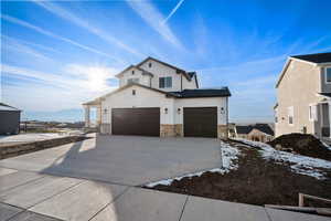 View of front of home with stone siding, concrete driveway, and board and batten siding