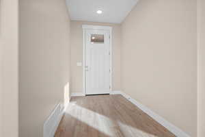Doorway featuring baseboards and wood finished floors