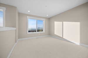 Empty room with light carpet and recessed lighting