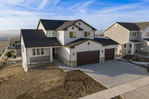 Modern inspired farmhouse with stone siding, driveway, board and batten siding, covered porch, and a mountain view
