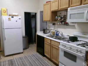 Kitchen featuring white appliances, light countertops, light tile patterned floors, and light brown cabinets