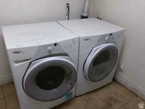 Washroom with light tile patterned flooring and independent washer and dryer