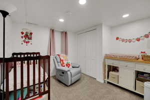 Bedroom featuring light carpet, a nursery area, recessed lighting, and a closet