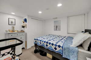Bedroom with light carpet, recessed lighting, and a closet