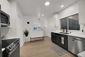 Kitchen with decorative backsplash, stainless steel appliances, white cabinets, pendant lighting, and recessed lighting