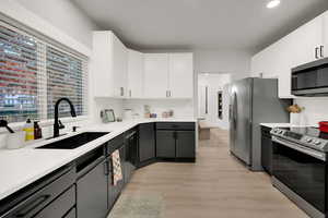 Kitchen with white cabinetry, stainless steel appliances, decorative backsplash, light wood finished floors, and recessed lighting