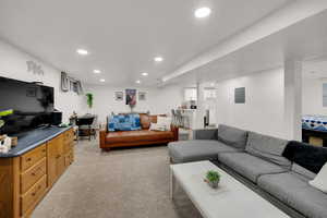 Living area with light carpet, recessed lighting, and electric panel