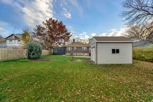 Fenced backyard featuring an outdoor structure