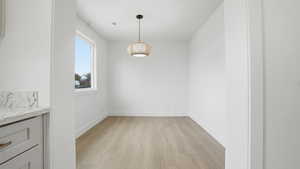 Unfurnished dining area featuring light wood-style floors and baseboards