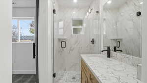 Bathroom featuring a marble finish shower and vanity