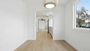 Hall with light wood-type flooring and healthy amount of natural light