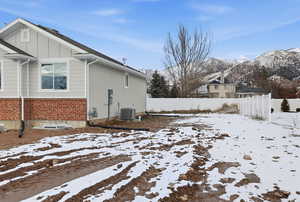 View of snow covered exterior with brick siding and board and batten siding