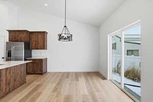 Kitchen with pendant lighting, a chandelier, light wood-style flooring, light stone countertops, and high vaulted ceiling