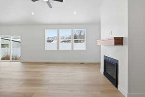 Unfurnished living room with a glass covered fireplace, light wood-type flooring, recessed lighting, and ceiling fan