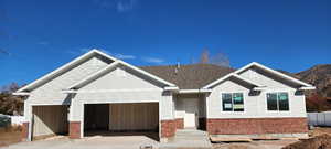 View of front of home featuring board and batten siding, a garage, driveway, and brick siding