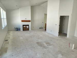 Unfurnished living room with high vaulted ceiling and a fireplace