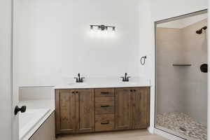 Bathroom with double vanity, a shower stall, and tiled tub