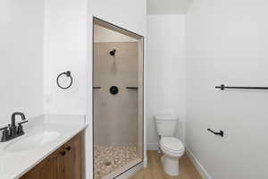 Bathroom with vanity, a tile shower, and light wood-style floors