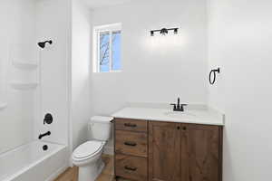 Full bath with vanity, washtub / shower combination, and light wood-style floors