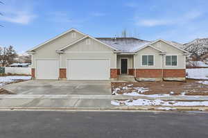View of front of home featuring board and batten siding, brick siding, a garage, and driveway