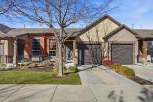 View of front facade featuring driveway, stucco siding, roof with shingles, a garage, and covered porch