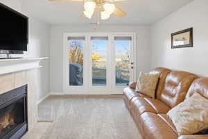 Living room with a fireplace, light carpet, and a ceiling fan