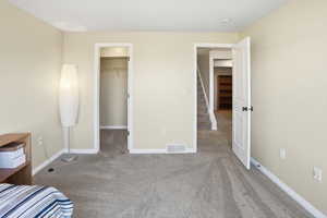 Unfurnished bedroom with carpet floors and a walk in closet