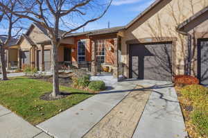 View of front facade with driveway, stucco siding, a porch, a front yard, and an attached garage