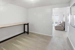 Empty room with light colored carpet and baseboards
