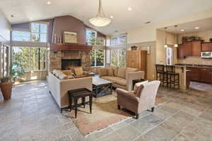 Club house living area featuring high vaulted ceiling, recessed lighting, stone tile floors, and a fireplace
