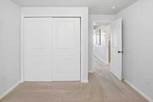 Unfurnished bedroom with light carpet and a closet