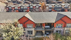 Back of house featuring a balcony, roof with shingles, and a residential view