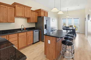 Kitchen featuring a center island, light wood-style floors, pendant lighting, brown cabinetry, and a kitchen bar