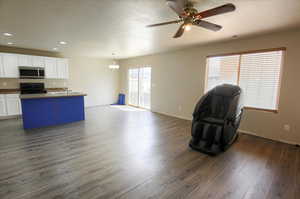 Kitchen featuring open floor plan, white cabinetry, black electric range oven, dark countertops, and a kitchen island with sink