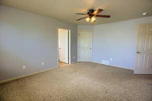 Owner's Suite bedroom with light colored carpet and ceiling fan