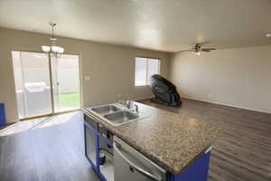 Kitchen with a center island with sink, open floor plan, dark wood-type flooring, decorative light fixtures, and blue cabinetry