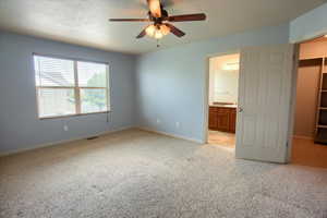Owner's Suite bedroom with light carpet, ceiling fan, connected bathroom, and a textured ceiling