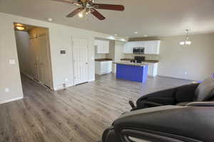 Living area featuring light wood-style flooring, ceiling fan, and recessed lighting