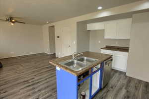 Kitchen with dark countertops, white cabinets, dark wood-style flooring, dishwasher, and open floor plan