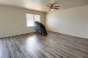 Living room featuring wood-style finished floors, a textured ceiling, and a ceiling fan