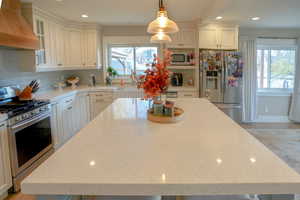Kitchen with premium range hood, appliances with stainless steel finishes, tasteful backsplash, white cabinets, and recessed lighting