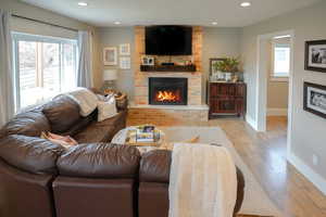 Living area featuring wood finished floors, plenty of natural light, recessed lighting, and a fireplace