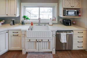 Kitchen featuring backsplash, stainless steel appliances, light stone counters, and dark wood-style flooring