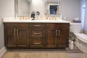 Bathroom with double vanity and dark wood-type flooring