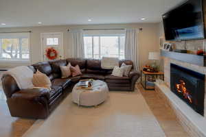Living room with light wood finished floors, healthy amount of natural light, a fireplace, and recessed lighting