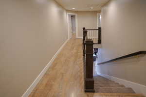 Staircase with wood finished floors and recessed lighting