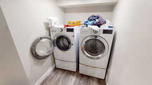 Laundry room with light wood finished floors and washing machine and clothes dryer