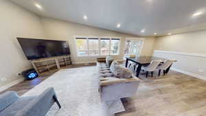 Living room with lofted ceiling, recessed lighting, light wood-style floors, and a textured ceiling