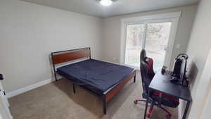 Bedroom with light carpet, a textured ceiling, and a desk